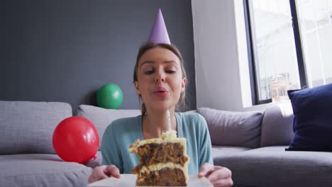 mujer con sombrero de fiesta soplando una vela en el pastel en casa