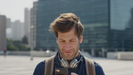 Retrato-De-Un-Joven-Atractivo-Usando-Un-Teléfono-Inteligente-En-La-Ciudad-Enviando-Mensajes-De-Texto-Navegando-Disfrutando-De-Un-Estilo-De-Vida-Urbano-Soleado-En-Cámara-Lenta-De-La-Ciudad