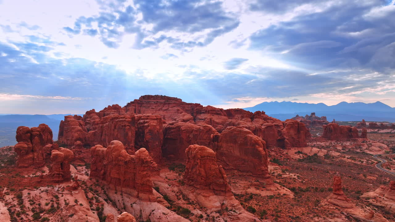 Approaching the beautiful red whimsical rocks with no vegetation. Overcast sky at backdrop. The Arches National Park in Utah, USA from aerial perspective