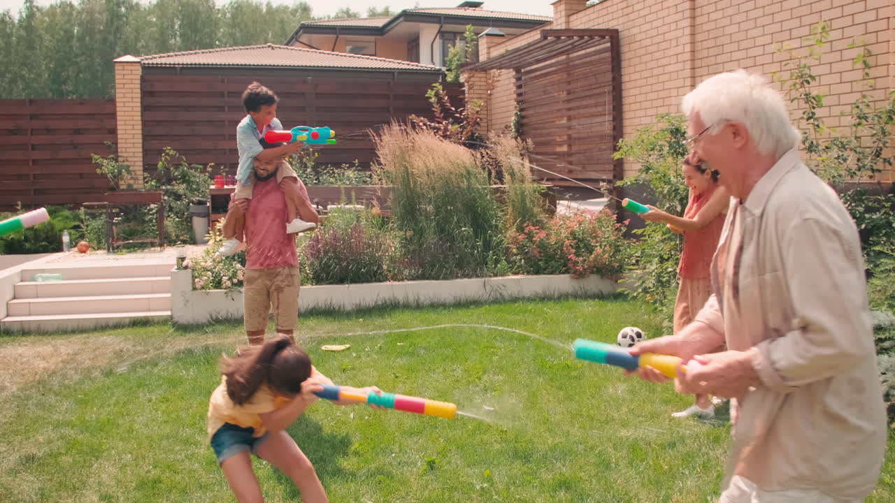 Joyful Family Playing With Water Pistols In Backyard