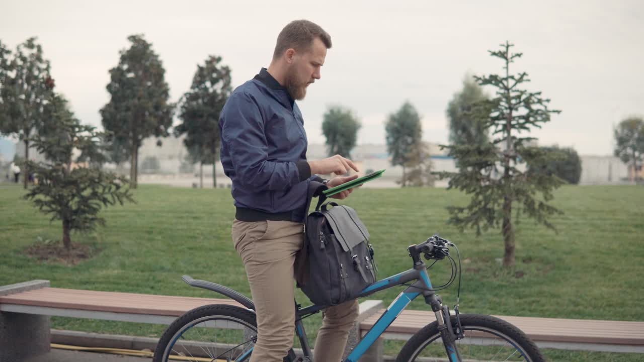 hombre de negocios con tableta y bicicleta en el parque