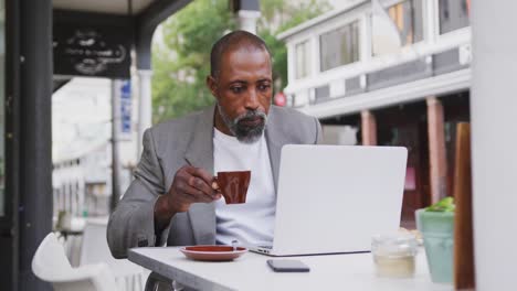 african american man drinking a coffee and using a laptop