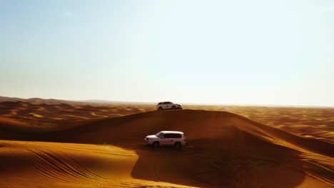 Aerial-view-of-4x4-off-road-land-vehicle-taking-tourists-on-desert-dune-bashing-safari-in-Dubai,-UAE