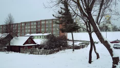 Russian-village-with-church,-wooden-cottages-and-Khrushchevka-pref-building