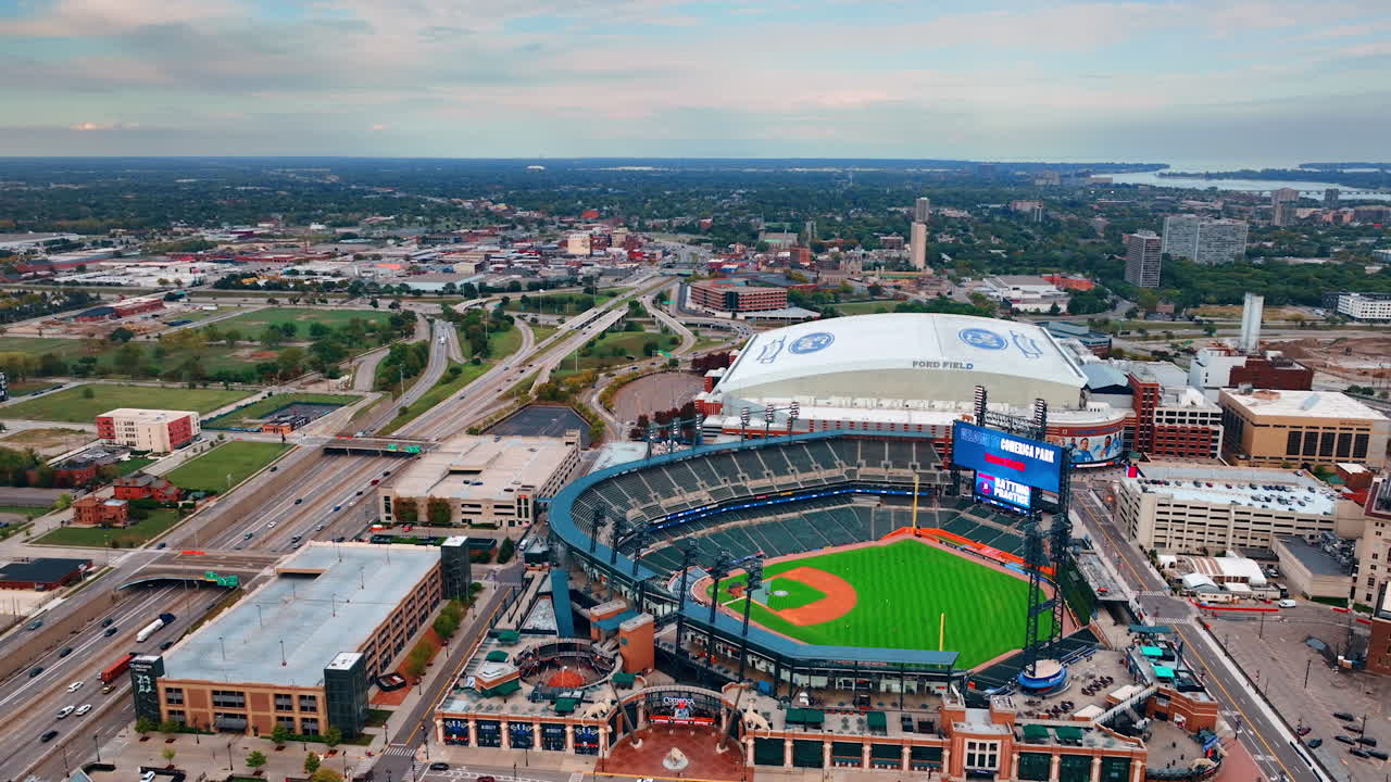 Cars move by the highways and freeways in Detroit, Michigan, USA. Approaching sport arena and stadium in the cityscape. Aerial view