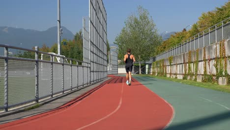 rear of a sporty man running on stadium track