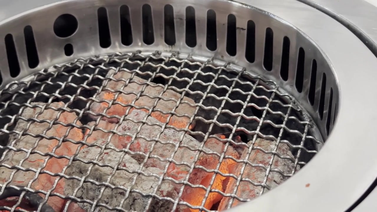 Primo piano di un barbecue vuoto con braci ardenti, calore che sale e atmosfera fumosa, pronto per grigliate e cucinare all'aperto