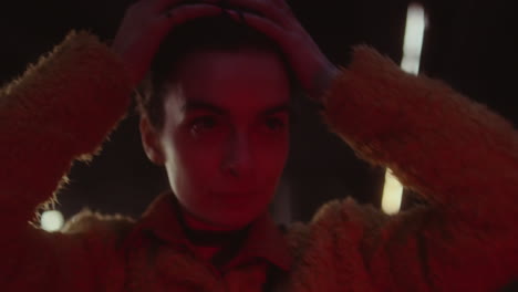 dramatic portrait of a woman fixing her hair in red lighting