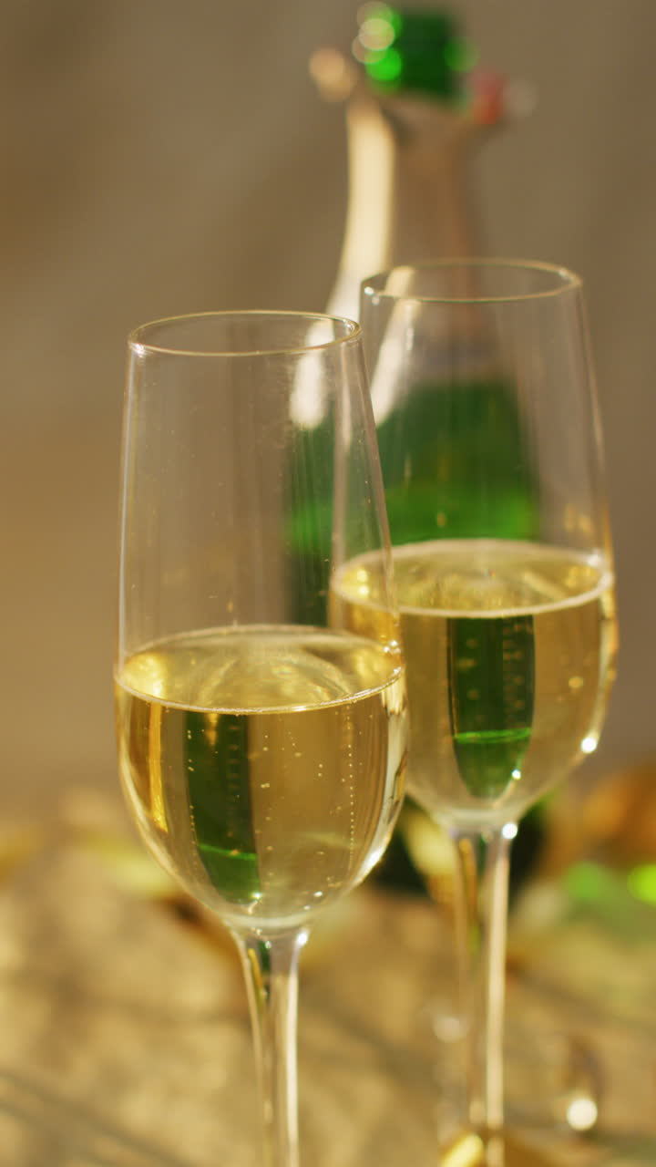 video vertical de dos vasos de champán y una botella de champán abierta en la mesa