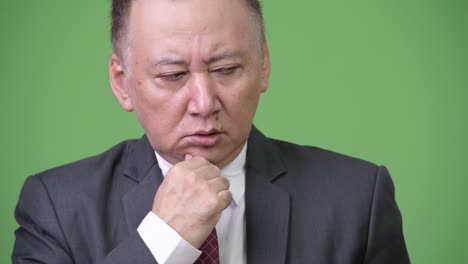 mature stressed japanese businessman looking down while thinking