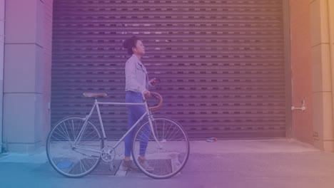 spots of light against asian woman using smartphone while walking with her bicycle on the street