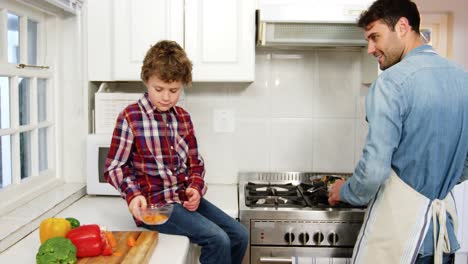 boy helping father while cooking food in kitchen