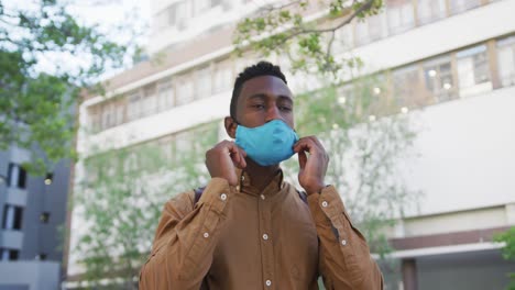 african american businessman adjusting face mask standing in street