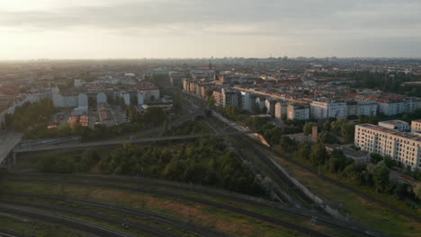 Aerial-panning-view-of-railway-junction-and-residential-district-in-large-city.-Shot-against-bright-morning-sunshine.-Berlin,-Germany