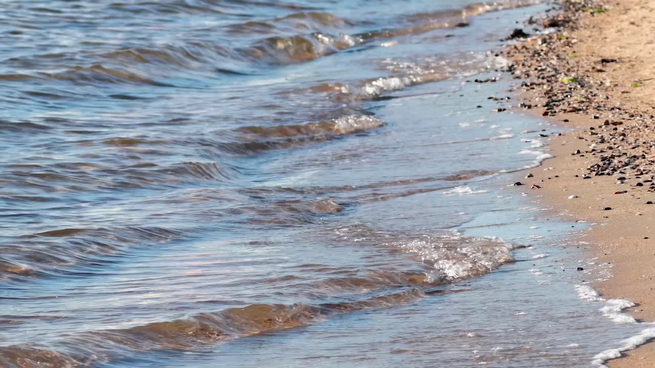 Small waves softly touch the pebbled beach, creating a calming and serene coastal scene.