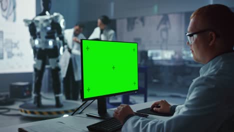 in development laboratory: chief analyst uses green screen computer, scientists and engineers work on a robotics exoskeleton prototype. designing exosuit to help disabled people, hard labor workers