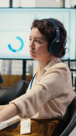 vertical video office administrator uses focus music on headset to solve tasks