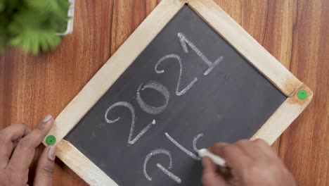 pov shot of hands writing 2021 plans on school slate - concept of new year 2021 planning