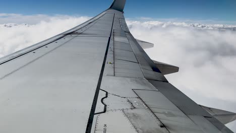 Passagieransicht-Des-Flugzeugflügels,-Der-über-Weiße,-Flauschige-Wolken-Gleitet