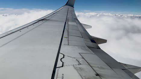 passenger view of aircraft wing skimming over white fluffy clouds