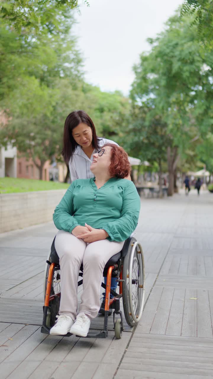 Woman in wheelchair with caregiver in a park