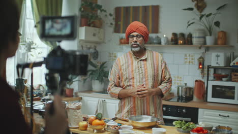 indian food blogger explaining recipe to camera while being filmed in kitchen