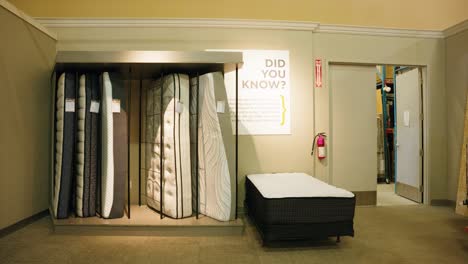 warehouse employee walks from storage area bedding gallery to inspect mattresses