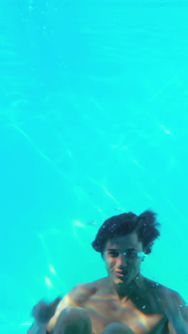 happy man jumping in swimming pool waving at camera