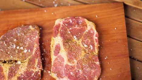 Topdown-shot-of-2-steaks-lying-on-a-wooden-board-on-a-table-close-up