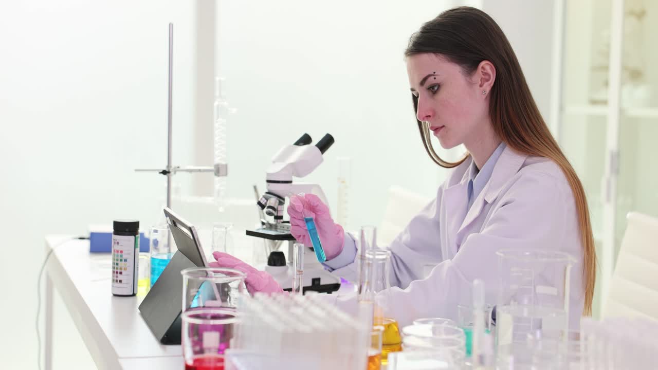 Female Scientist Working in a Laboratory with Test Tubes and Tablet