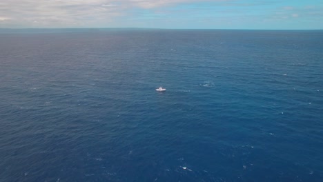 isolated boat in open sea, pull back aerial view with stunning endless horizon