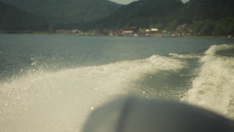 foamy water splashes behind sailing ship on calm water on summer day closeup. white trace on azure ocean surface after motorboat at sunny resort