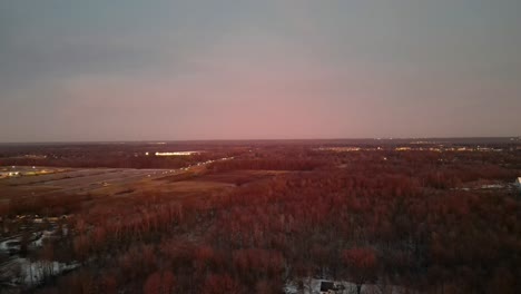 aerial view of a landscape under a stunning sunset, with a hint of city lights in the distance, showcasing the transition from natural beauty to urban life.
