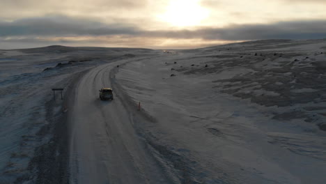 aerial view, car on icy road in highland of iceland with stunning sky on horizon , cinematic drone shot