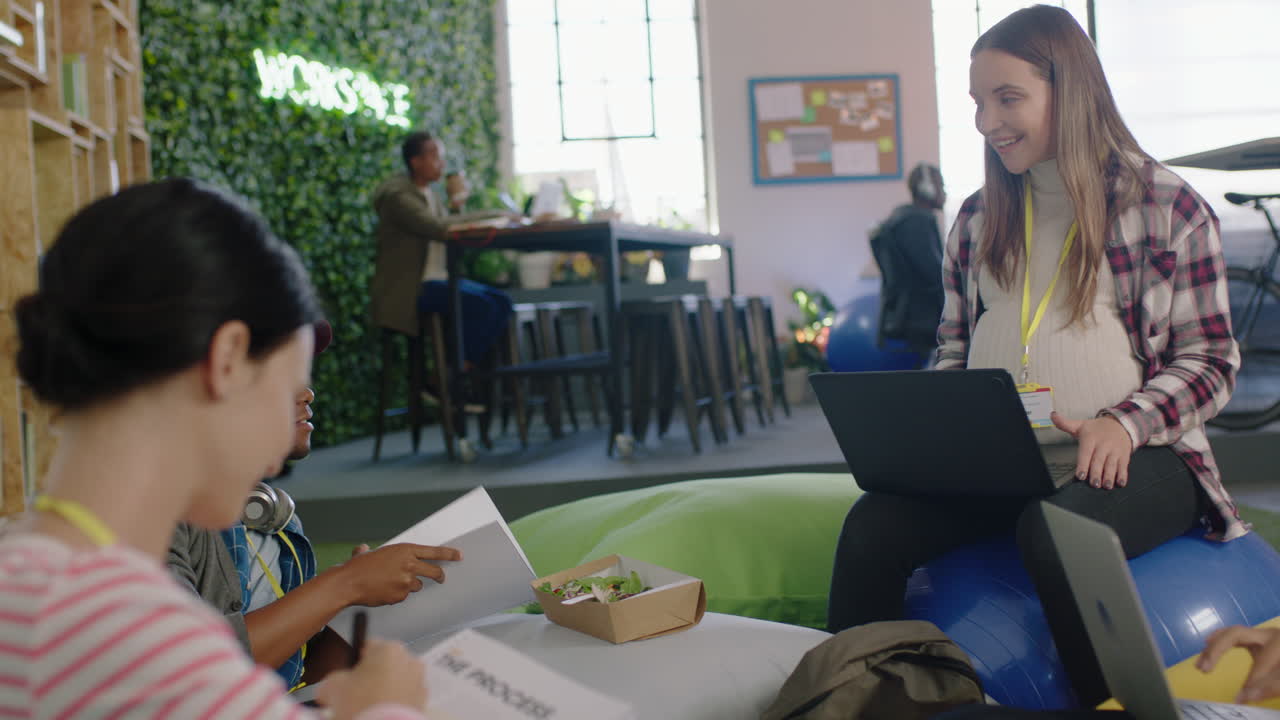 젊은 사업가들이 모여 브레인스토밍을 하고 임신한 팀 리더 여성이 팀워크 프로젝트를 논의하고 동료들과 문서를 공유하고 성공적인 스타트업 사무실에서 협력합니다.