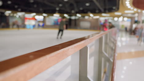 a blurred view of a skiing background featuring people skiing. highlighting the polished handrail in the foreground and the active environment of the skiing area