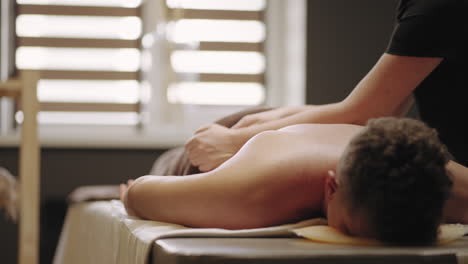 relajarse masaje en la clínica osteopática hombre está acostado un entrenador profesional y masajista está masajeando su espalda