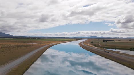 Car-driving-along-the-shore-of-a-perfect-blue-river-in-new-Zealand