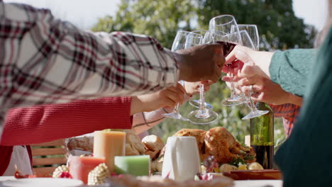 happy diverse male and female friends toasting on celebration meal in sunny garden