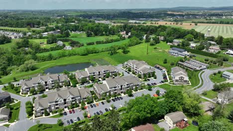 noble american apartment buildings with pond in green suburb district of town. sunny day in spring. new building housing architecture in usa. aerial tilt down shot.