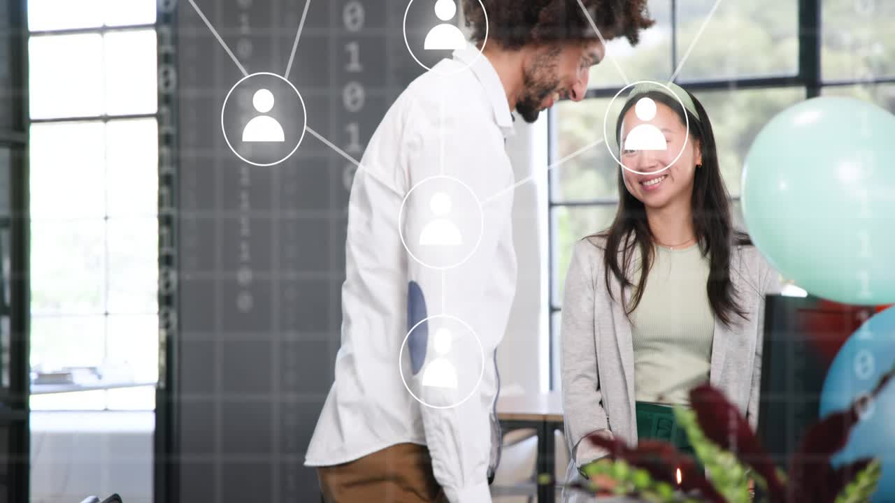 Man at desk turning as woman bringing lit cake, office network graphics linking team celebrating