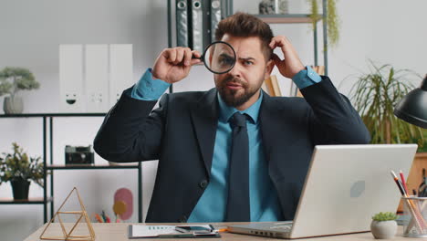 business man holding magnifying glass near face looking with big zoomed eye searching analysing