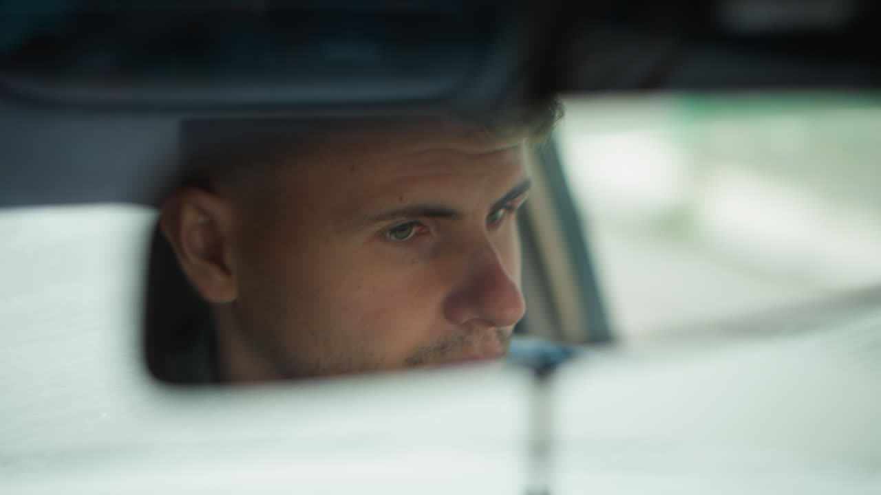 homem branco em close-up focado na estrada, com luz do dia refletida no espelho retrovisor, bokeh suave, clima reflexivo, passageiro examinando a faixa, motorista de aplicativo de transporte verificando o GPS, motorista de entrega monitorando