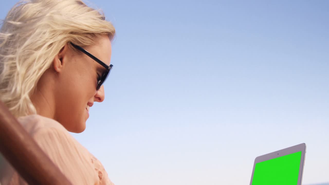 mujer acostada en su silla de sol con su tableta