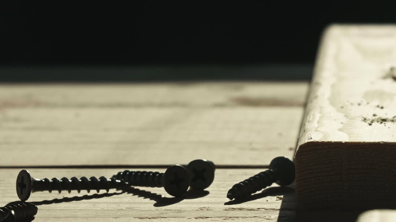 Wood screws in silhouette on work surface, Tilt Up, Slow Motion