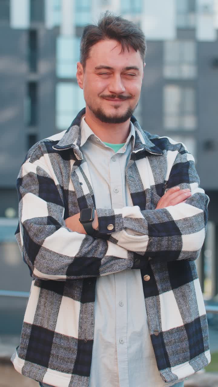 retrato de un hombre maduro caucásico feliz girando y mirando a la cámara con los brazos cruzados en la calle