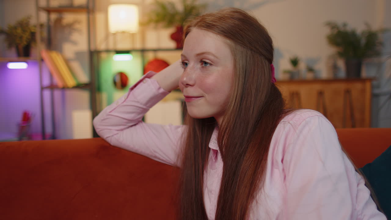 행복하고 평온한 젊은 여자가 미소 짓고, 멀리 바라보며, 꿈을 꾸고, 휴식을 취하고, 좋은 소식을 듣고, 집에서 사랑에 빠진다.