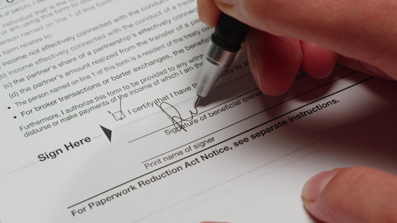 Hand Signing a Document and Checking a Box with a Pen