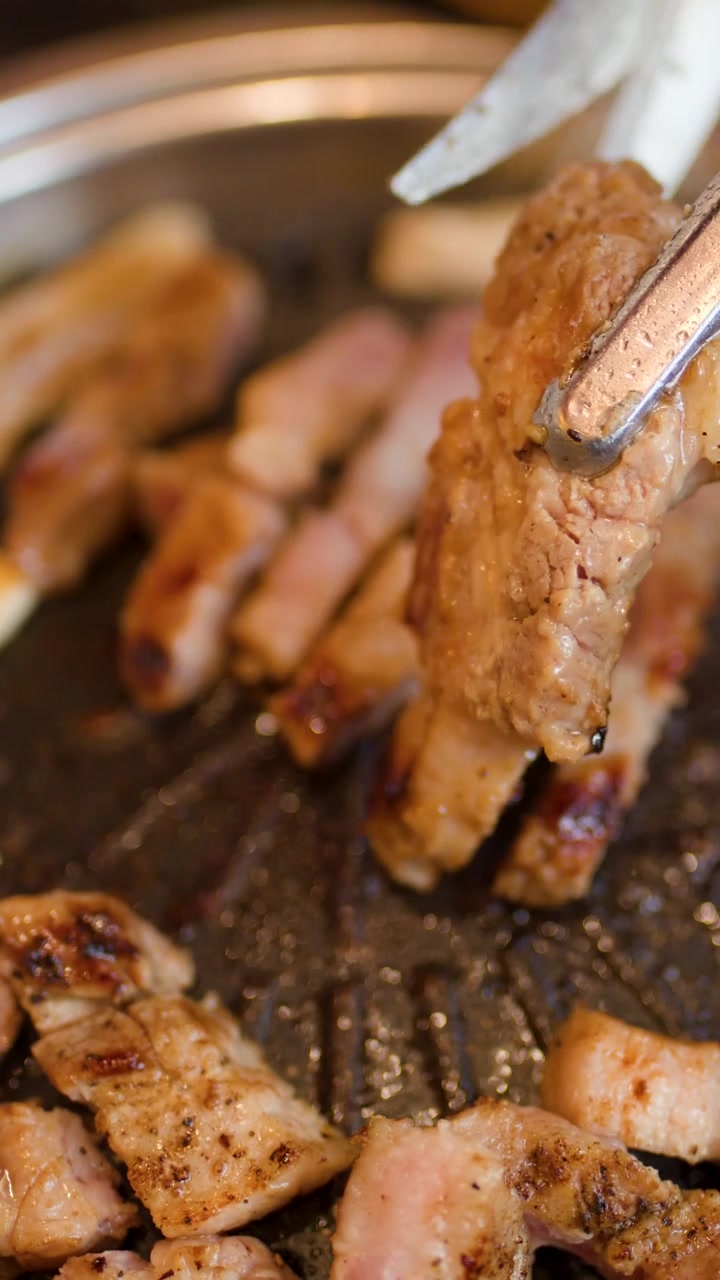 Pancetta di maiale sfrigolante tagliata su una griglia per barbecue coreano