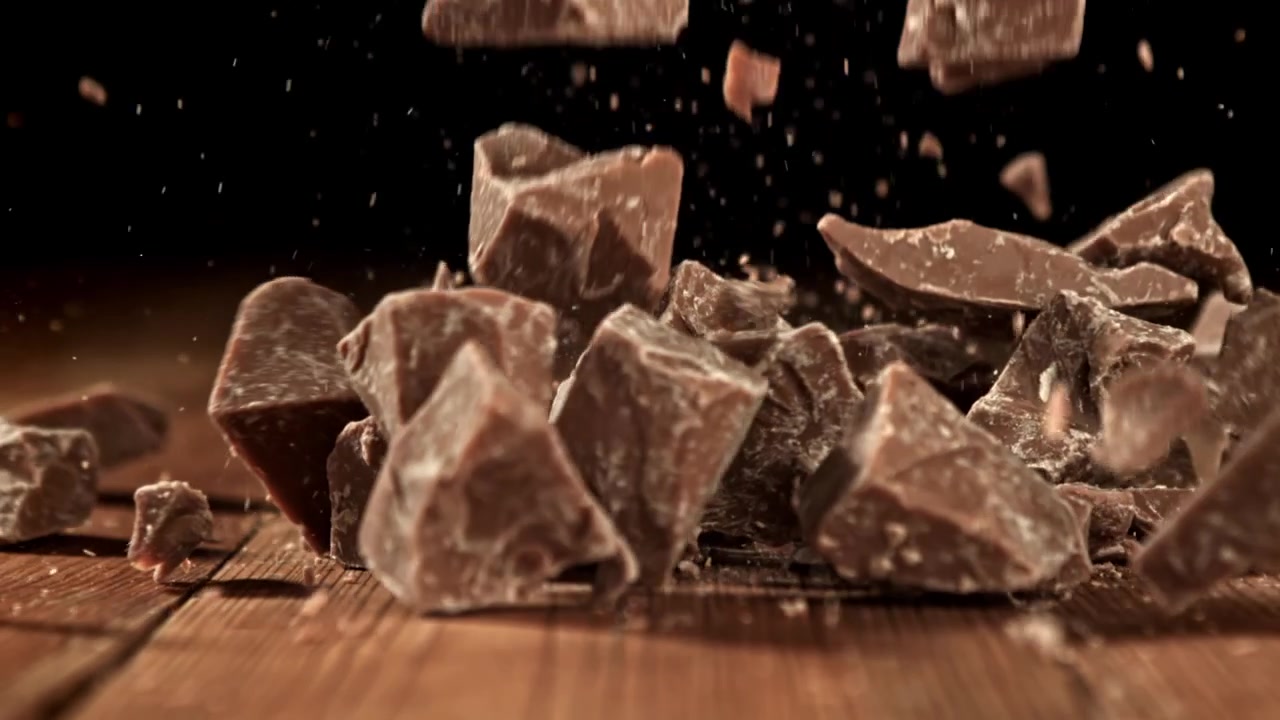 Pezzi di cioccolato che cadono su un tavolo di legno al rallentatore